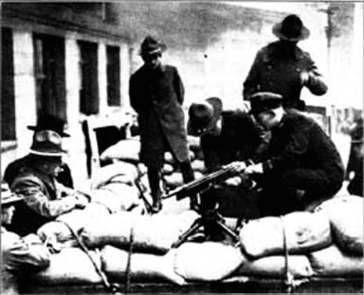Police setting up a mounted machine gun during the strike behind a barricade of sandbags. By The Town Crier newspaper, February 15,1919 - http://digitalcollections.lib.washington.edu/cdm/singleitem/collection/social/id/2956/rec/7, Public Domain, https://commons.wikimedia.org/w/index.php?curid=72402259
