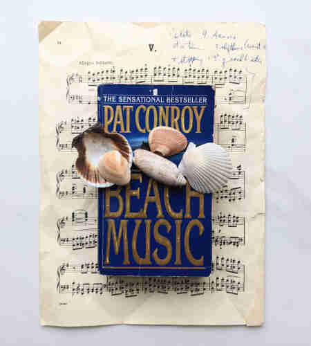 A piece of sheet music, the book, Beach Music by Pat Conroy, and some sea shells. 