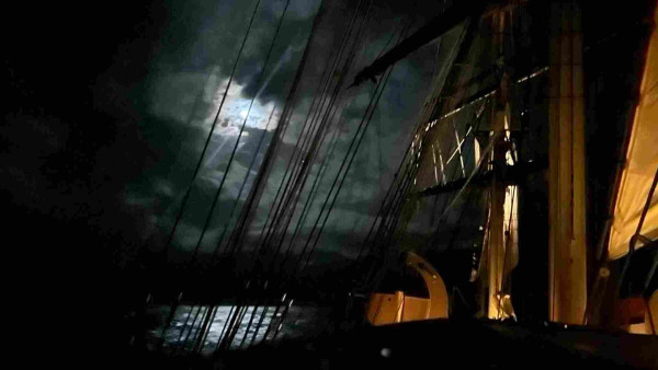 Moon visible through the rigging of a tall ship. 