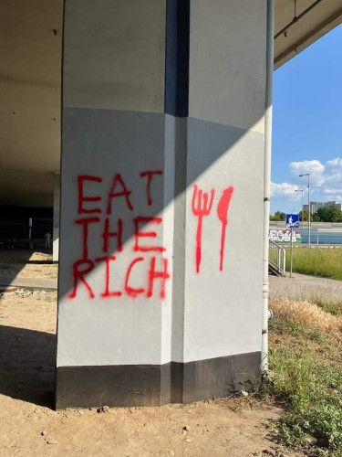"Eat the Rich" written on a bridge support beam using red spray paint