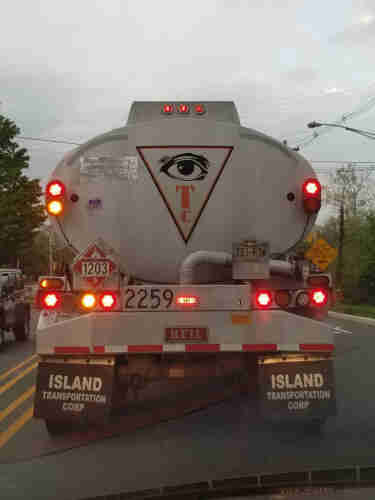 White truck with a logo that has a weird upside down triangle with an eye inside it.