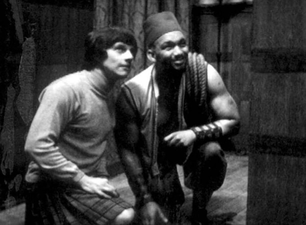 Picture from Evil of the Daleks

Jamie (Frazer Hines) dressed in a long sleeved shirt and kilt kneeling on the ground looking up. 

Next to him is Kemel (Sonny Caldinez) wearing a fez, armlets, and a turkish vest, rope coiled on his shoulder, also kneeling and looking up. 
