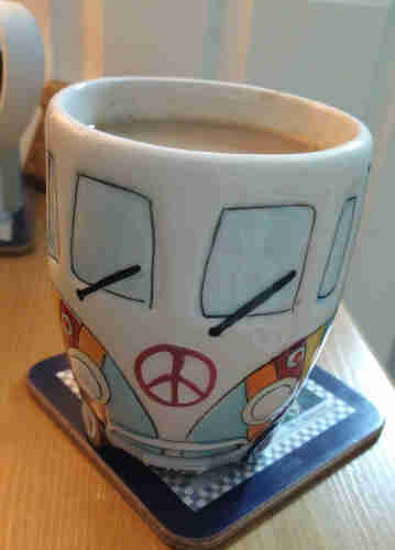 Mug of tea on a bedside cabinet, it looks like the front of a VW Camper with two windows and wipers at the top