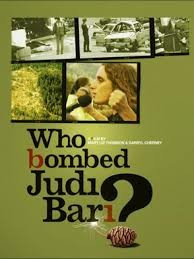 This is a poster for Who Bombed Judi Bari. Poster shows image of Bari speaking to supporters, with a raised fist. It also shows the remains of her bombed out car, law enforcement, and Cherney speaking in front of a Redwood Summer banner. The poster art copyright is believed to belong to the distributor of the film, the publisher of the film or the graphic artist. By https://www.imdb.com/title/tt1754621/, Fair use, https://en.wikipedia.org/w/index.php?curid=64097552