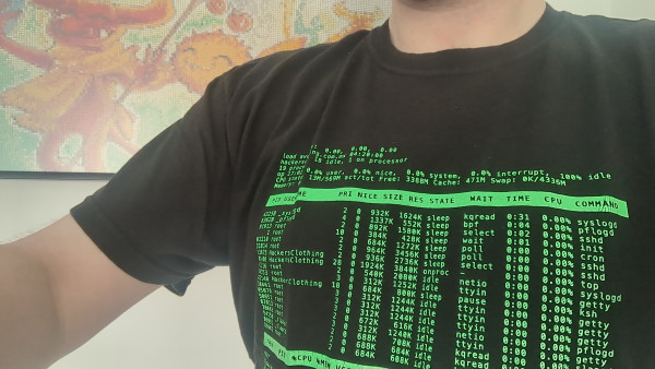 White person wearing a dark shirt with OpenBSD top printed on it in a green color