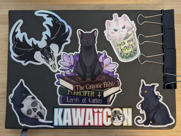 Photo of a sketchbook cover with various stickers of cats