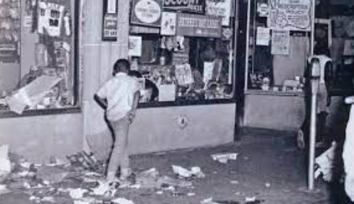 Cincinnati, during the 1967 riots. Image of broken shop windows and glass and litter on the sidewalk.