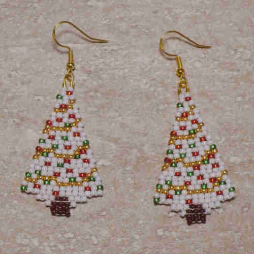 Native beaded white Christmas tree earrings on a stone background