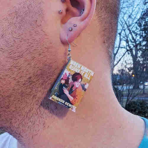 an earring with the cover of Amanda DeWitt's Wren Martin Ruins it All