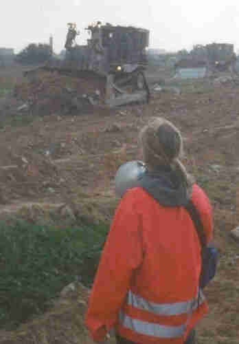 Rachel Corrie stands before Israeli IDF Caterpillar D9 bulldozers. She is wear a bright orange jacket and holding a bullhorn. By Joe Carr. joecarr@riseup.net is the email address found on the biographical info page: http://www.lovinrevolution.org/Bio.htm - archived here. See index by date.derivative work: Gobonobo (talk) - Rachel_Corrie_2003_March_16.jpg. Original source is http://www.lovinrevolution.org/rachel_pictures.htm - archived here. See index by date., Copyrighted free use, https://commons.wikimedia.org/w/index.php?curid=10552803
