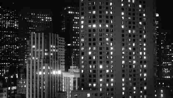 This is a photo in black and white, shot out of a hotel window at night.
Skyscrapers. Lots of them. Many windows are still lit.
Location is San Francisco