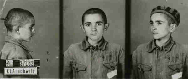 A mugshot registration photograph from Auschwitz. A boy with a shaved head wearing a striped uniform photographed in three positions (profile and front with bare head and a photo with a slightly turned head with a hat on). The prisoner number is visible on a marking board on the left.