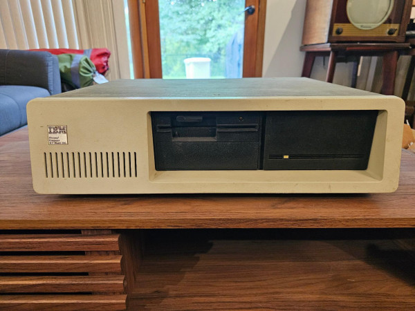 Front view of a very dirty IBM 5162 computer sitting on a coffee table