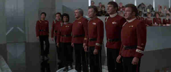 A shot from Star Trek 4: The Voyage Home, with all the main characters up front in line, facing a judge.  In the background, the observers sit looking on.
