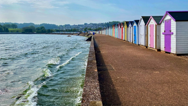 Beach huts lining the promenade along Broadsands Beach. The high tide right up against the sea wall, the beach completely underwater 
