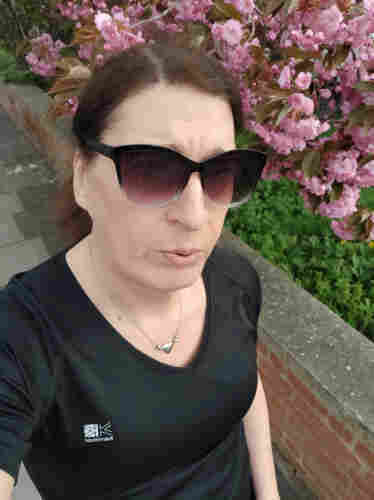 A selfie of a brunette woman in black running gear and sunglasses exhaling ie out of puff
