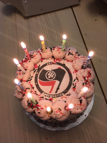 A delicious (& vegan!) Antifa International 10th anniversary cake, with candles aglow!