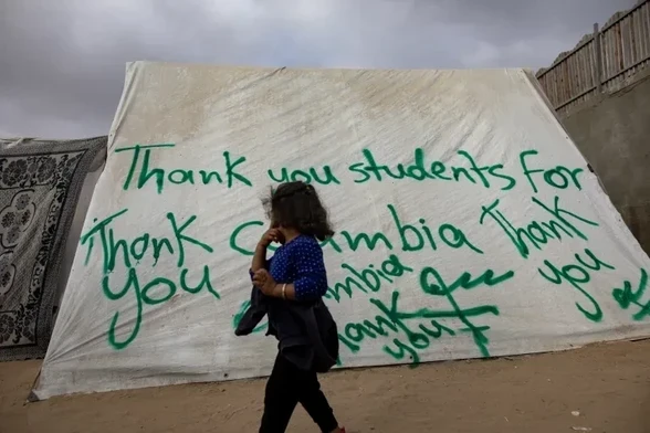 A Palestinian child walks past a tent with a ‘thank you’ message dedicated to students at Columbia University in New York, at the Rafah refugee camp in southern Gaza on Saturday [Haitham Imad/EPA]