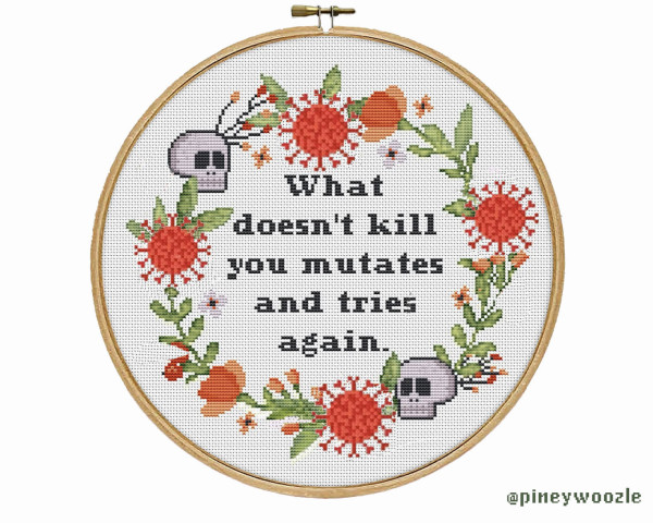 An embroidery hoop with a wreath of flowers embroidered on it where the flowers have been replaced by small skulls and COVID molecules and with these words in the center of the wreath. What doesn’t kill you mutates and tries again. The image is signed @Pineywoozle