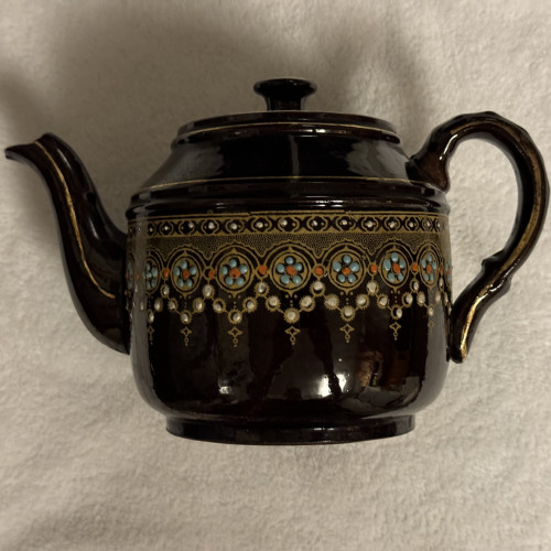 Photo: small brown teapot with elaborate lace-like design around the body in white, gold, turquoise and red. 