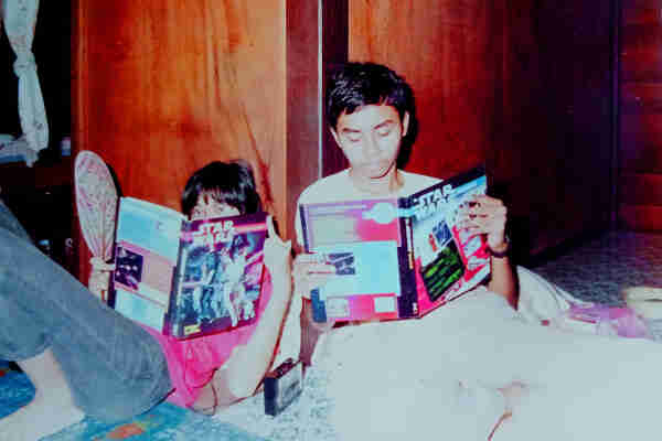 Two teenagers on the floor with their backs to the wooden wall, reading the Star Wars RPG and the Star Wars Sourcebook published by West End Games.