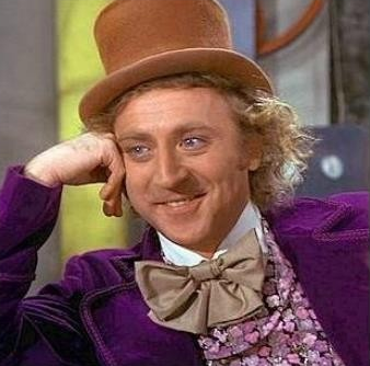 Willy Wonka character in a brown top hat and purple coat leaning on one hand and smiling.