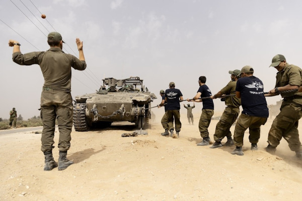 IOF soldiers assisting in directing an armored personnel vehicle damaged by the Resistance in Gaza in May 2024