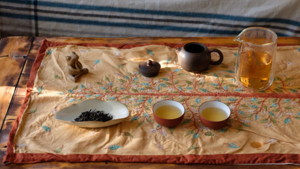 tea leaves, liquor, cups, tea pet, pot on table cloth