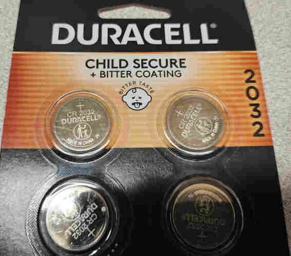 A pack of 4 CR2032s. The packaging says "Child secure + bitter coating" and a bitter taste iconograph with a baby sticking out their tongue