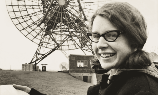 Jocelyn Bell Burnell standing in front of a radio telescope.
