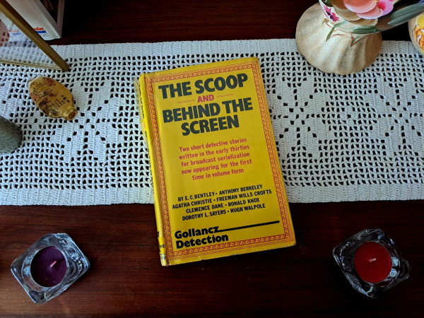 Livro publicado nos anos 80 com as primeiras colaborações dos membros do The Detection Club, originalmente criadas para a rádio (BBC). O livro é amarelo e estás sobre uma mesa de madeira.