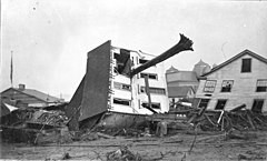 The John Schultz house in Johnstown after the flood. Skewered by a huge tree uprooted by the flood, the house. By Unknown author - https://web.archive.org/web/20170805012341/http://www.phmc.state.pa.us/bah/dam/rg/, Public Domain, https://commons.wikimedia.org/w/index.php?curid=90485452