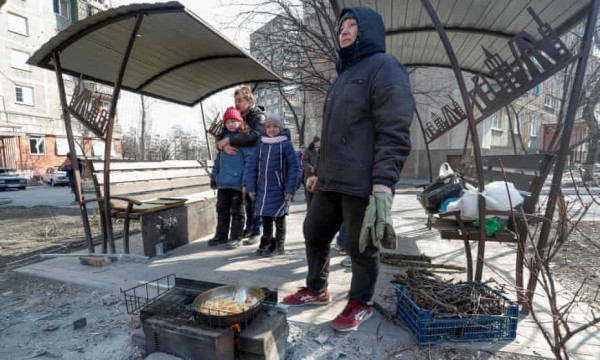 People prepare food in a yard in the besieged southern port of Mariupol, Ukraine, on 23 March 2022. Photograph: Alexander Ermochenko/Reuters