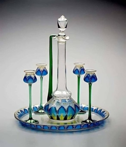 Beautiful set of decanter and four small blue flasses on tall green stems, all on a matching, mirrored tray. They look like flowers. They're made from glass and very delicate. 

Art Nouveau decanter and glasses, circa 1900-1905. Meyr's Neffe glass factory, Bavaria 


