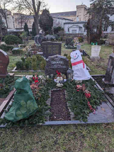 A Christmas-themed headstone and plot in the Dorotheenstädischer cemetery in Kreutzberg, Berlin. The plot has a fake snowman and Christmas tree, and is covered in evergreen wreaths with red ribbons. The headstone reads 

ROTTER
Heinz
28 8 1939 - 25 10 2011