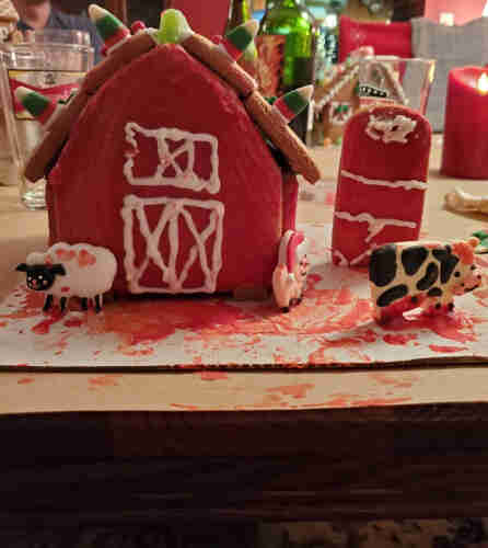 Gingerbread barn covered in red icing that looks like blood. The cow, sheep, and pig are all a bloody icing mess.