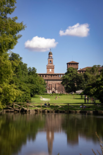 Vista del castillo Sforza (Milán) desde el parque Sempione durante una tarde casi estival y reflejado en un estanque.