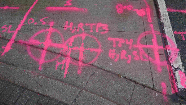 Pink symbols and acronyms spraypainted on the street