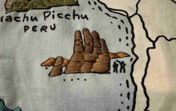 An embroidered version of Mano del Desierto. Shows a rock coloured hand emerging from the ground. 