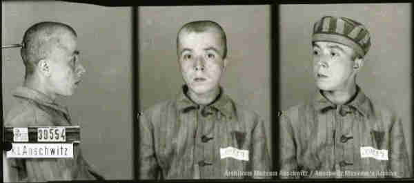 A mugshot registration photograph from Auschwitz. A man with a shaved head wearing a striped uniform photographed in three positions (profile and front with bare head and a photo with a slightly turned head with a hat on). The prisoner number is visible on a marking board on the left.