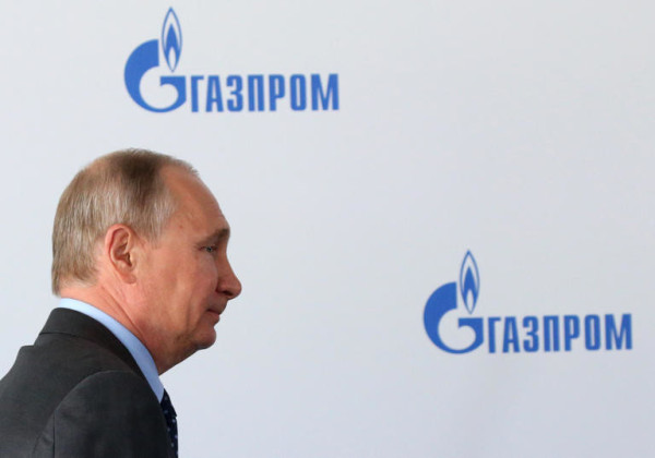 Russian President Vladimir Putin at the Amur Gaz Processing Plant on August 3, 2017 in Svobodny, Amur Oblast, Russia next to a sign that says "Gazprom".