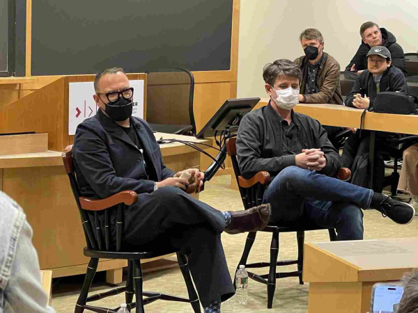 Corey Doctorow and Randall Monroe, seated in fancy wood chairs at the front of a Harvard classroom. 