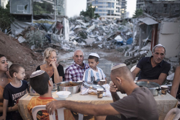 Three families hold an improvised, outdoor Shabbat dinner after their homes were demolished following a years-long struggle against eviction without proper compensation, at Givat Amal, Tel Aviv Jaffa, on September 19, 2014. (Activestills.org)