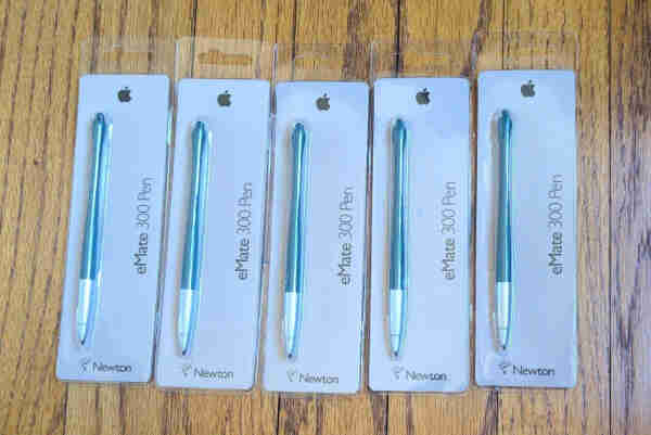 Five Newton eMate 300 Pens in individual blister packs. Black Apple logo at the top, Newton and lightbulb logo at the bottom. Each pen has a metallic end where you grip it and a green body.