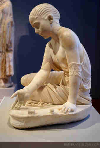 The motif of a seated young girl dates to a late Hellenistic model, which in the Roman version was supplemented by the game gesture. The astragalus (knucklebone) game is often depicted on funerary reliefs. Together with the portrait-like features of the girls, this motif suggests a sepulchral purpose of the sculpture.  