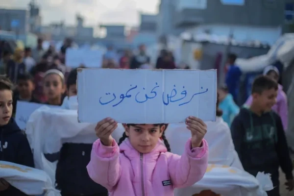 A young girl in pink jacket holds a sign in Arabic saying "We refuse to die."
Rafah, 14 February