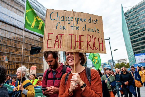 A protester carries a placard during a climate change demonstration march. The sign reads: Change your diet for the climate. Eat the Rich.