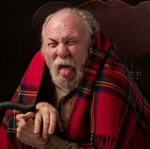 Old man with a beard, wrapped in blanket , with tongue out