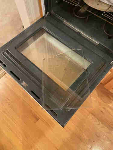 lower oven door (oven works but can't be controlled due to bad control panel) with broken glass from upper oven door laying on it