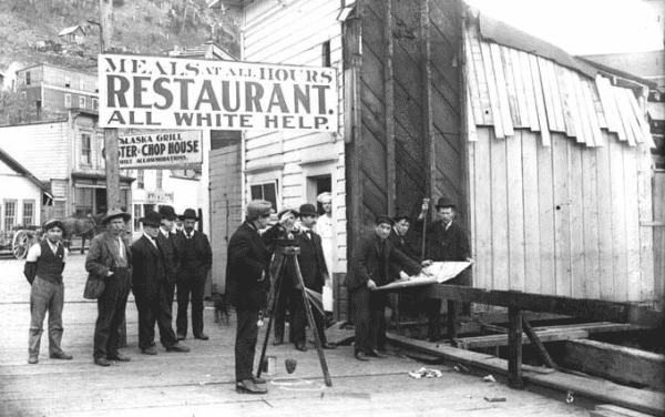 Discrimination in a restaurant in Juneau, Alaska in 1908. White men standing beneath a sign that reads, "All White Help." By Unknown author - http://historicalaska.blogspot.com/2011/06/racism-and-jim-crow-in-alaska.html, Public Domain, https://commons.wikimedia.org/w/index.php?curid=96027537